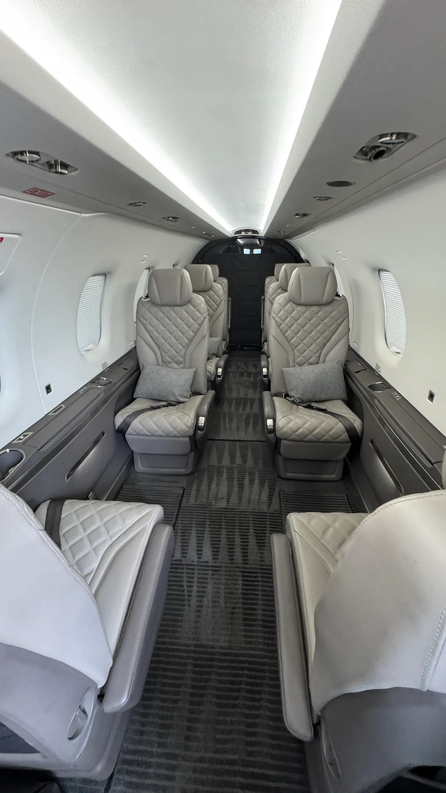 A close-up view of two light grey quilted leather seats in the rear of an aircraft cabin.
