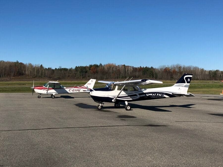 Two Cessna 172 aircraft, one white and red (C-GYPE) and one blue and white, parked on a tarmac.