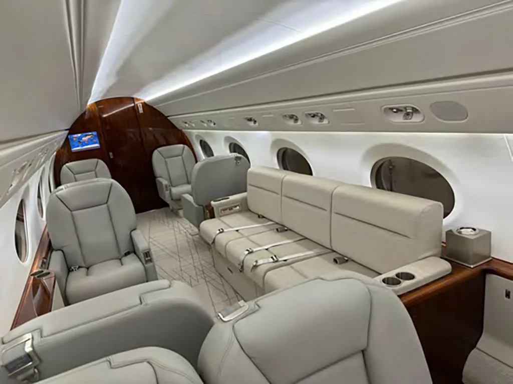 A comfortable section of the aircraft cabin with light gray leather seats and a matching sofa.