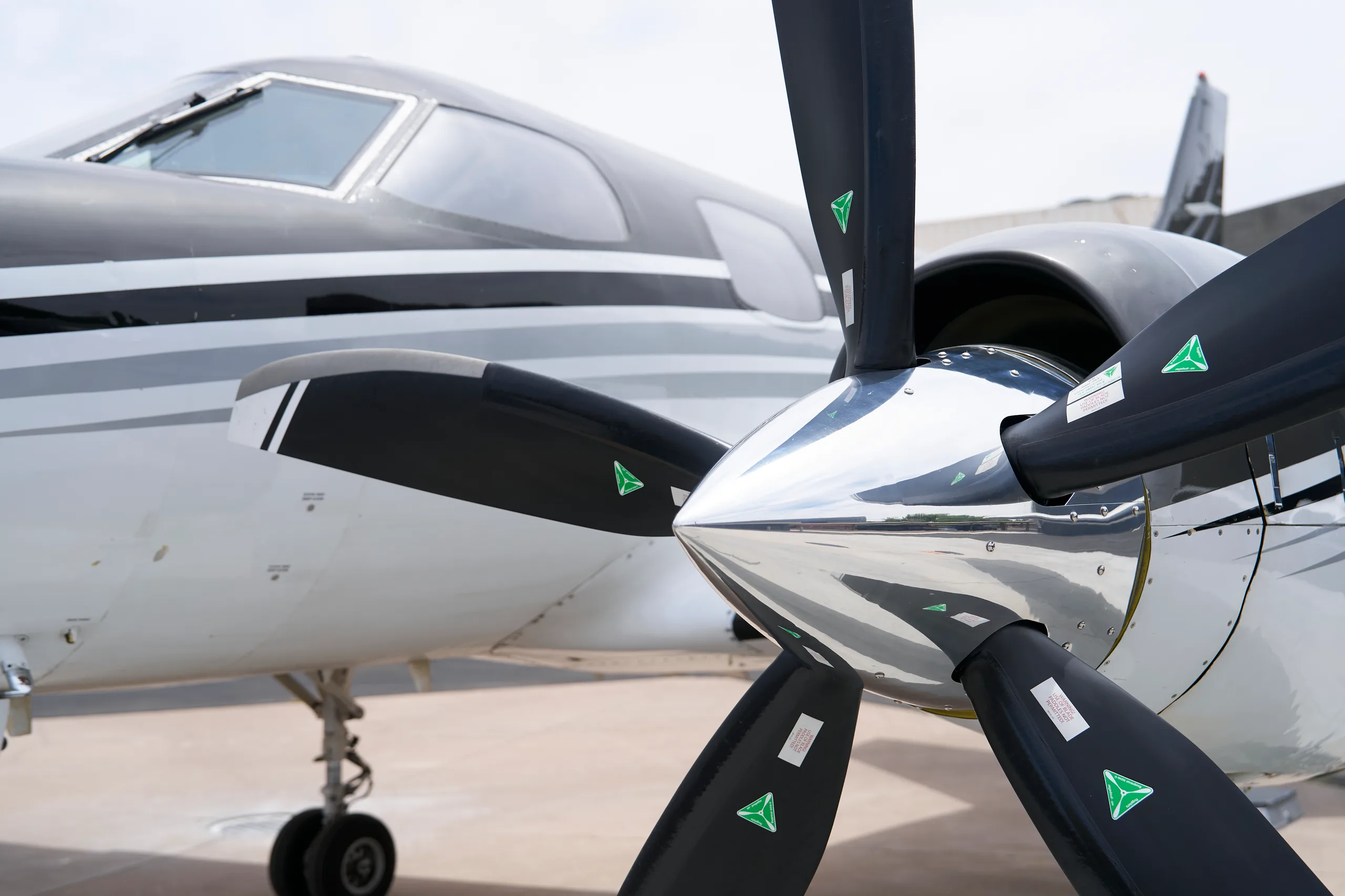 A close-up view of the polished propeller and nose of the white and black twin-engine turboprop aircraft.