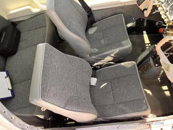 The interior of a small aircraft shows two grey fabric passenger seats from an overhead view.