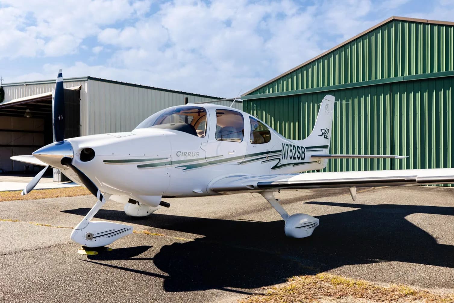 A front three-quarter view of the white Cirrus SR22 aircraft, registration N752SB, parked on an asphalt ramp.
