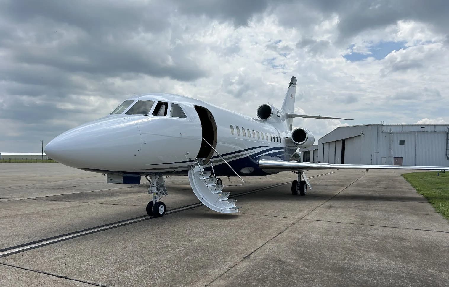 Front view of a white and blue aircraft with stairs extended.