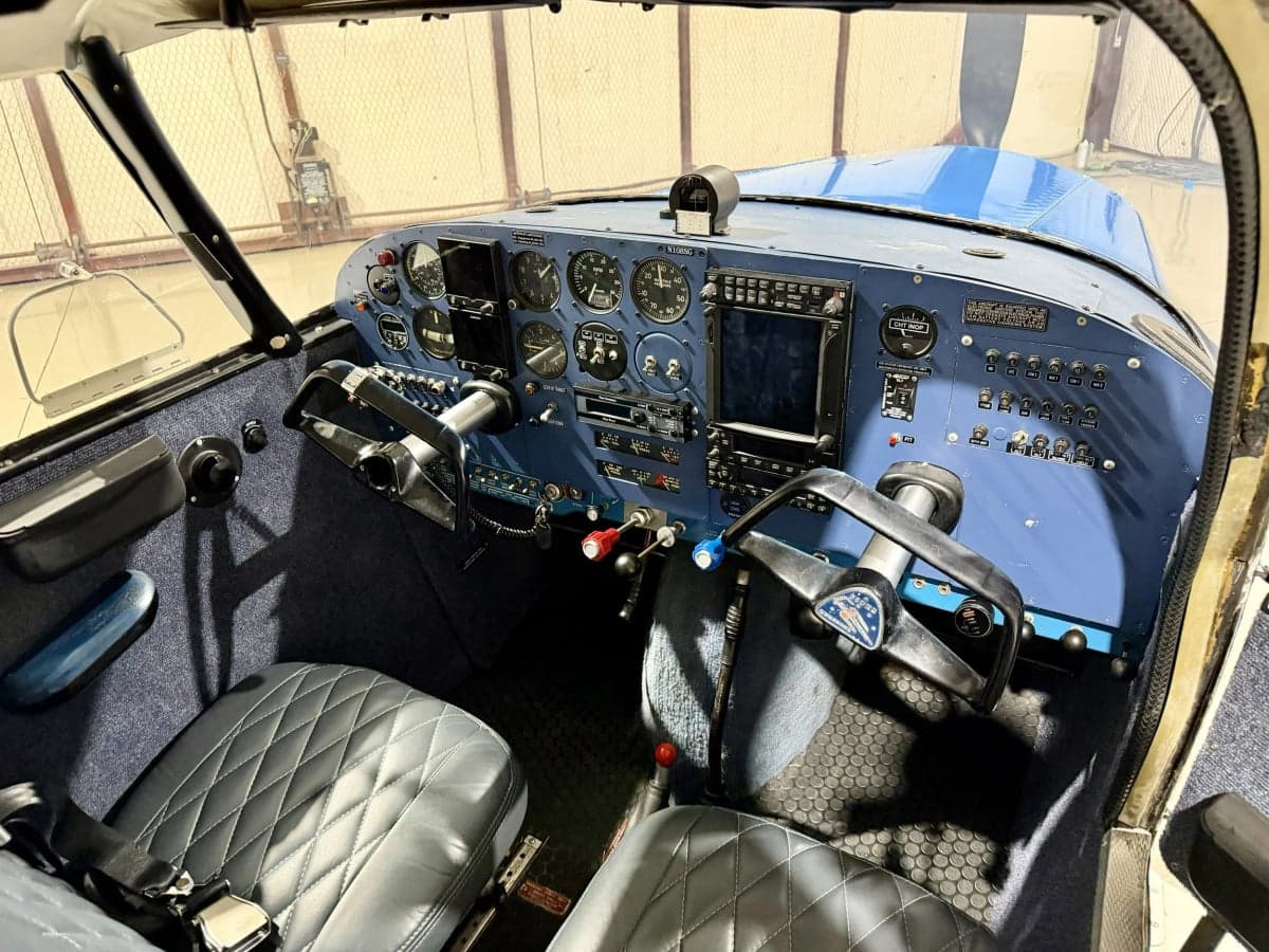 The cockpit of the Piper PA-28-140 Cherokee features a blue instrument panel and gray leather seats.