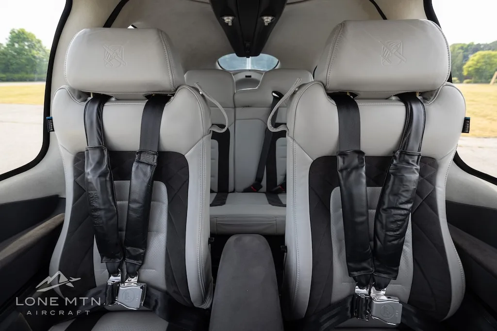 The light gray and black front passenger seats of an aircraft interior are shown from the rear.