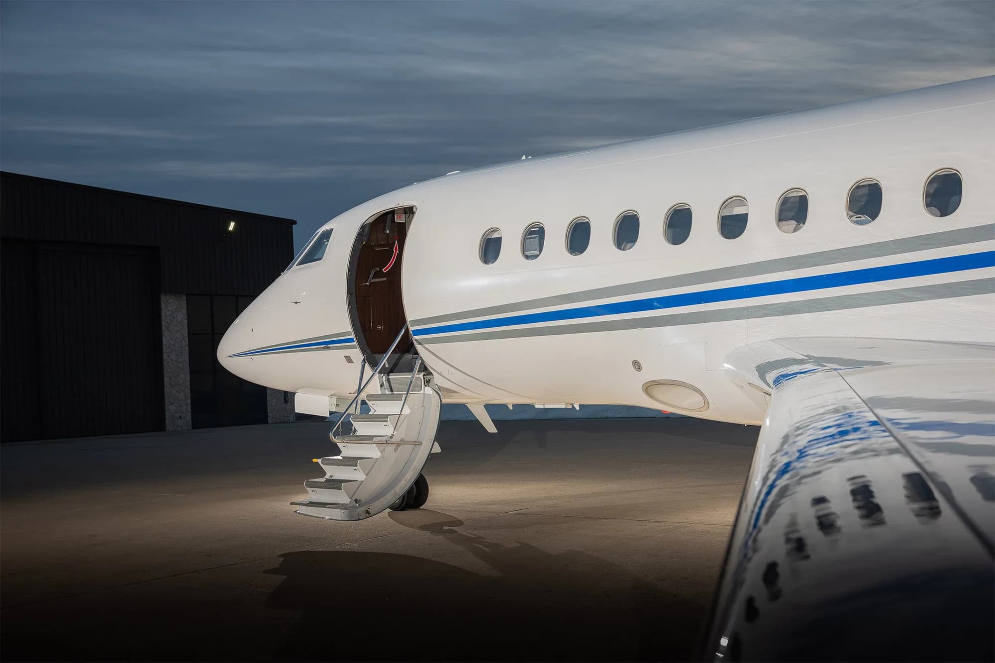 Close up of the front of a white jet with an open door and stairs extended.