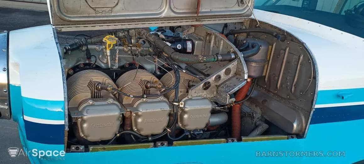 The engine compartment of a light aircraft with the cowling open, revealing a Continental engine.