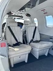 Interior view of the aircraft cabin with white leather seats.