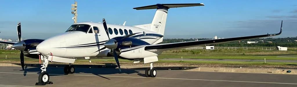 A close-up side view of a white and dark blue twin-turboprop aircraft on an airport tarmac.