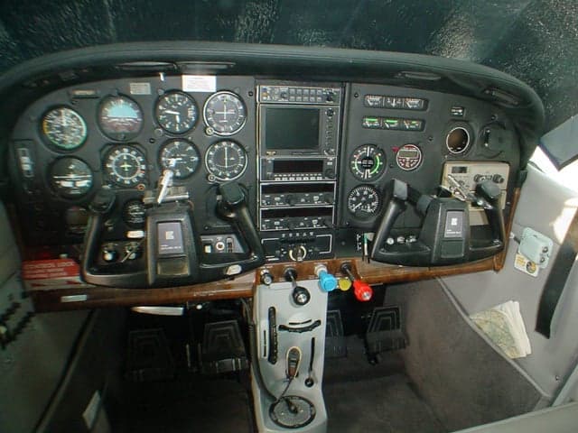The cockpit instrument panel of a small aircraft, featuring a mix of analog gauges and a central digital display.