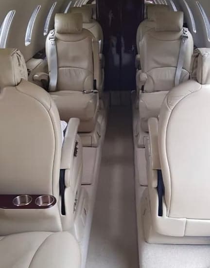 A view down the aisle of the aircraft cabin with tan leather seats.