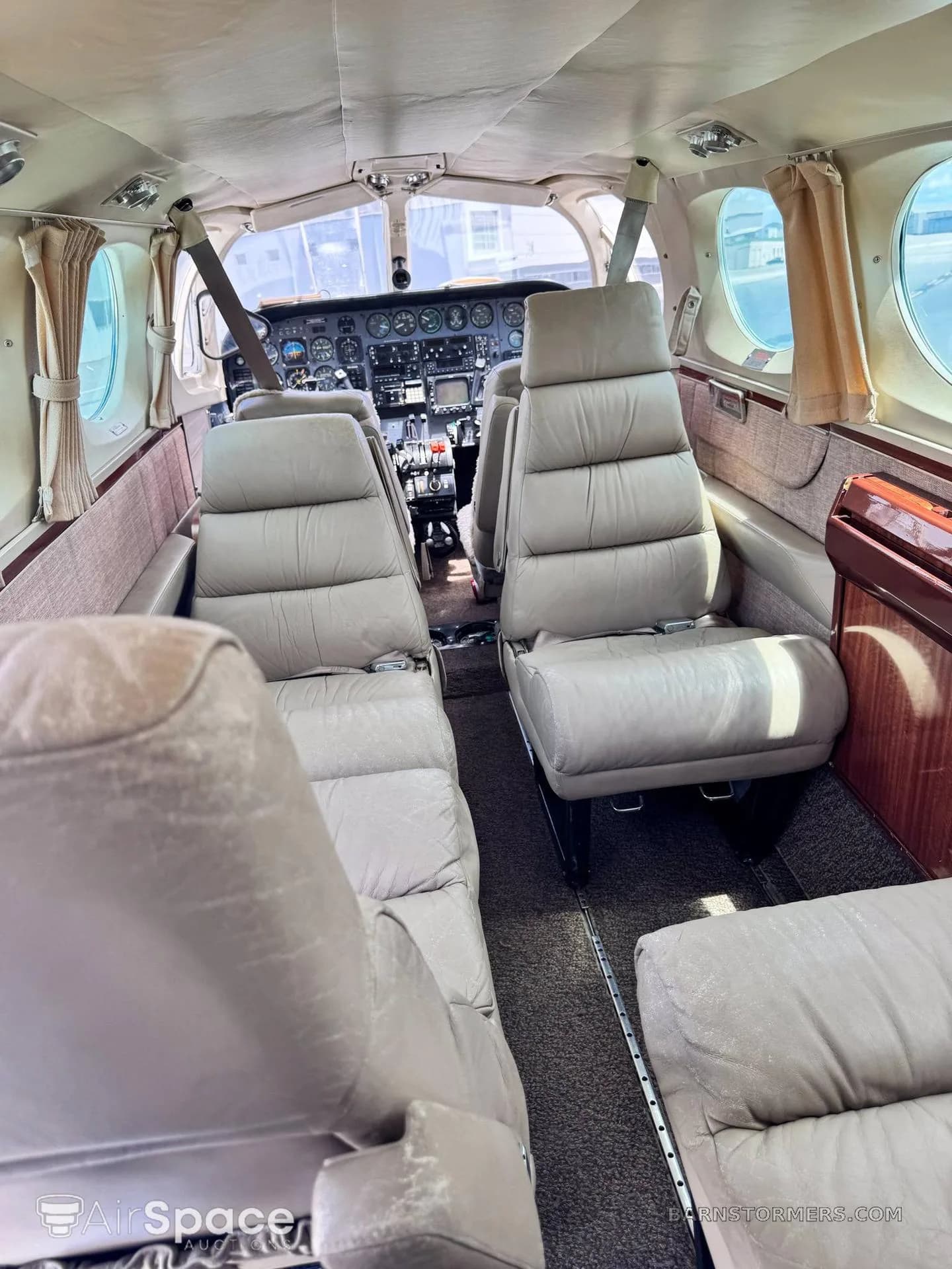 The aircraft's cabin interior with beige leather seats and a view towards the cockpit.