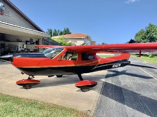 A Cessna Cardinal RG with a red and black paint scheme is parked on the tarmac.