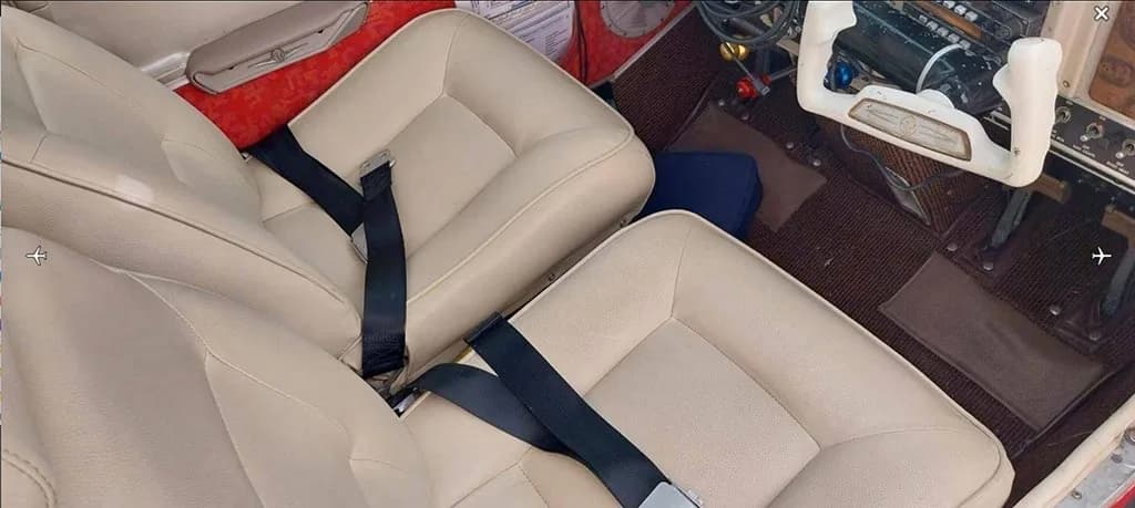 An overhead view of the light beige front seats in the aircraft's cabin, with a white control yoke visible.