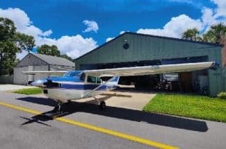 A Cessna 172 Skyhawk, registration N3374U, parked outside a hangar on a sunny day.