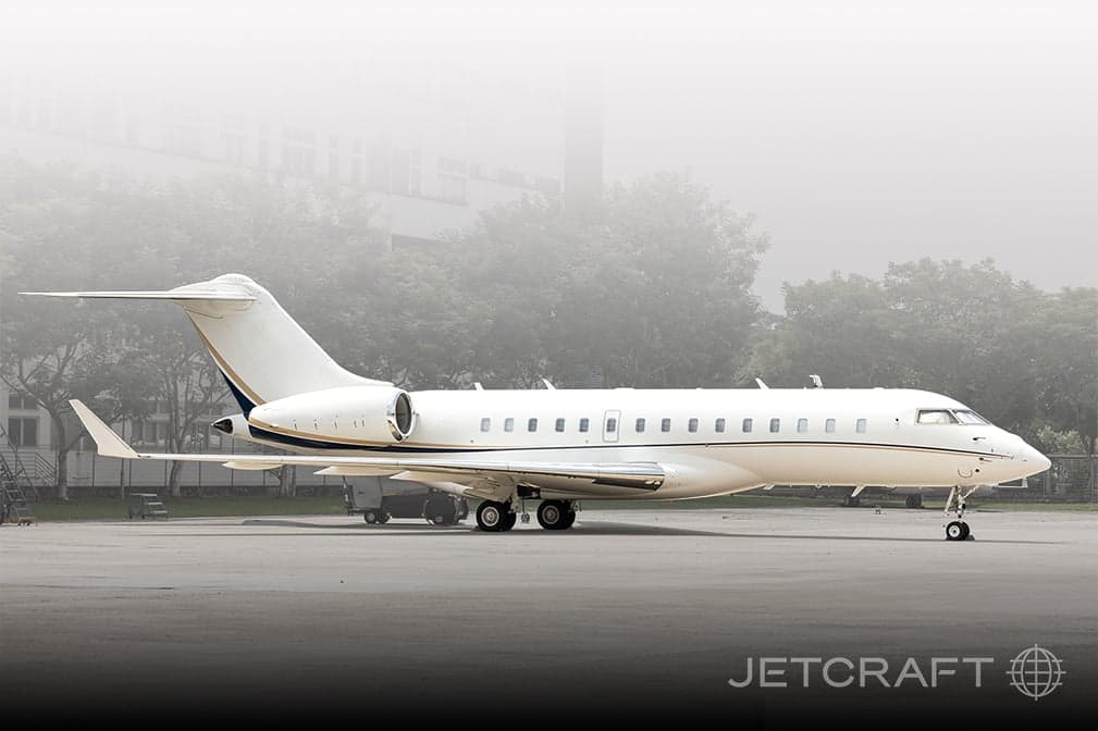 Side view of a white and gold Bombardier Global Express on the tarmac.