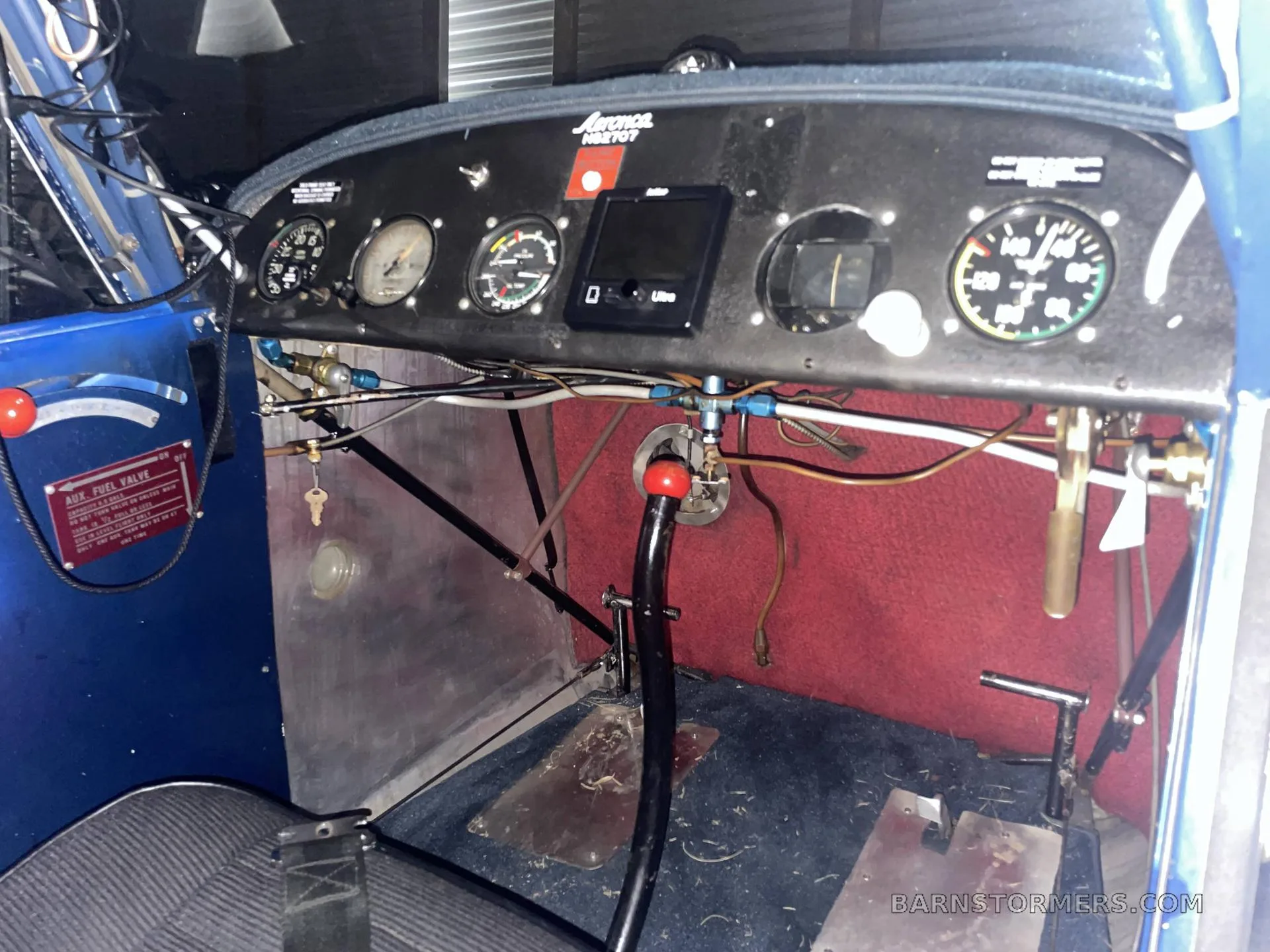 The instrument panel and controls of an Aeronca aircraft, featuring gauges, a fuel valve, and rudder pedals.