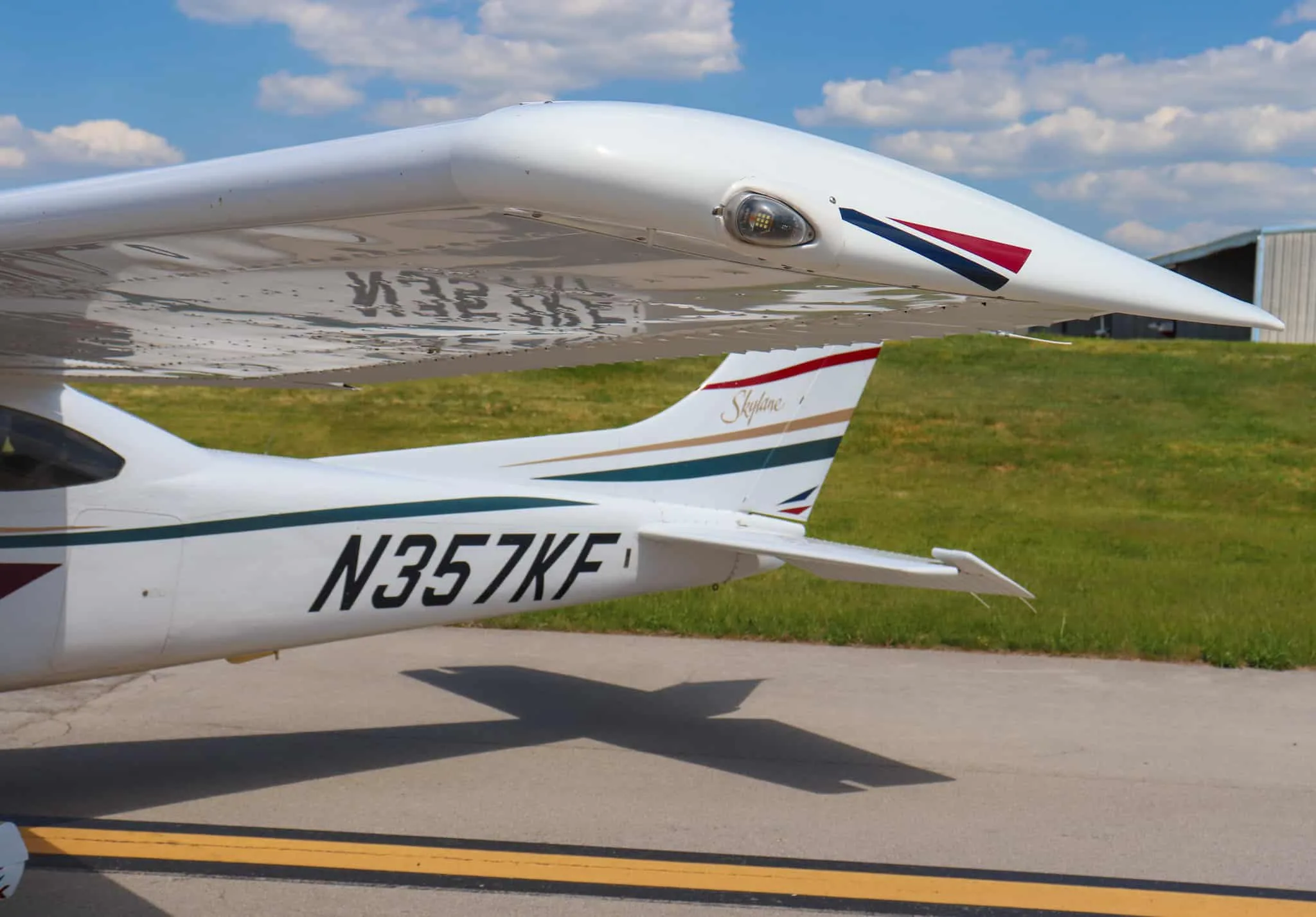 A close-up of the wingtip and tail of a white Cessna 182 Skylane showing the N-number and "Skylane" script.