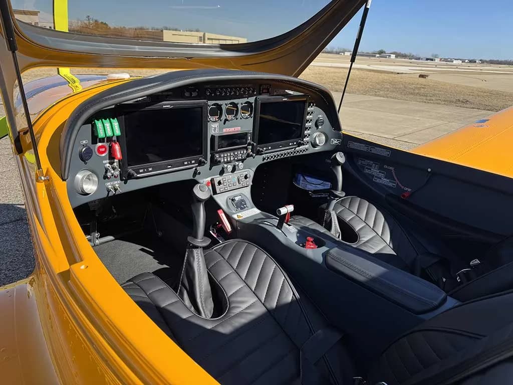 The cockpit of the yellow Bristell aircraft, N279SS, shows the instrument panel with dual screens and black quilted seats.