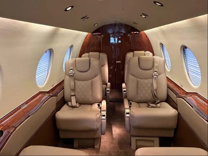 Aircraft cabin with tan leather seats and wood trim.