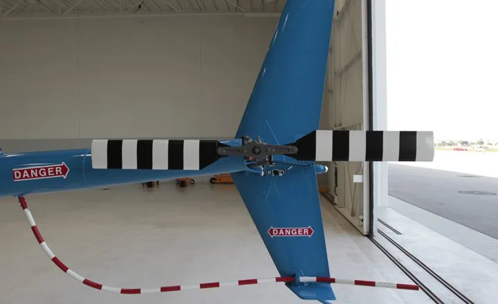 Tail rotor of a blue Robinson R44 helicopter in a hangar.