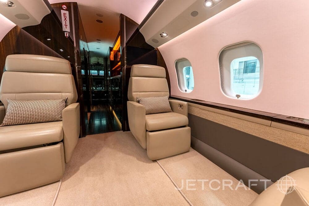 Interior view of a Bombardier Global Express business jet with beige leather seats.