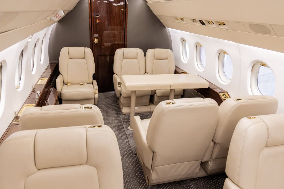 A view of the aircraft's interior, featuring beige leather seats and a central aisle.