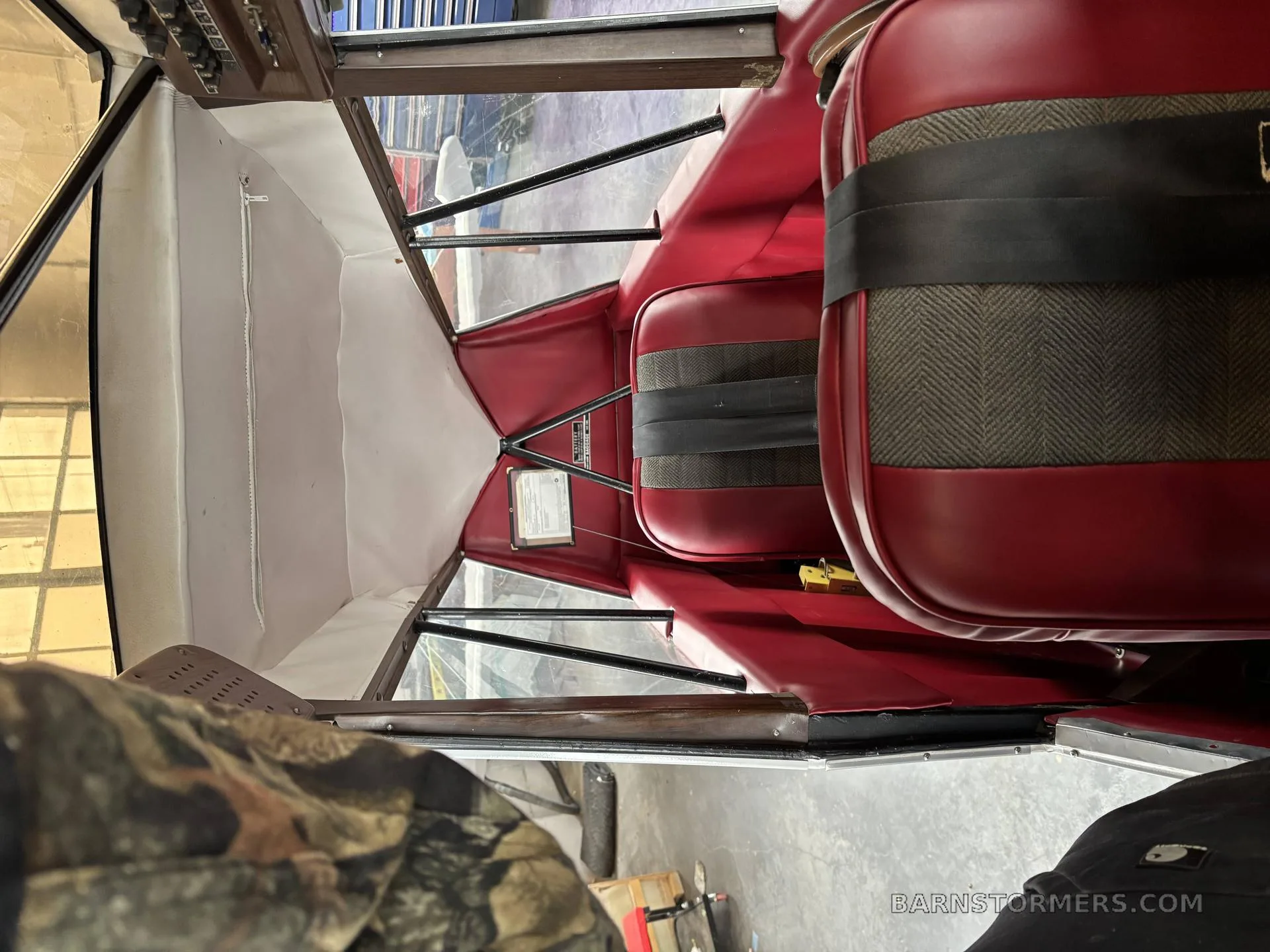 The interior cabin of a light aircraft, featuring red upholstered seats with fabric inserts.