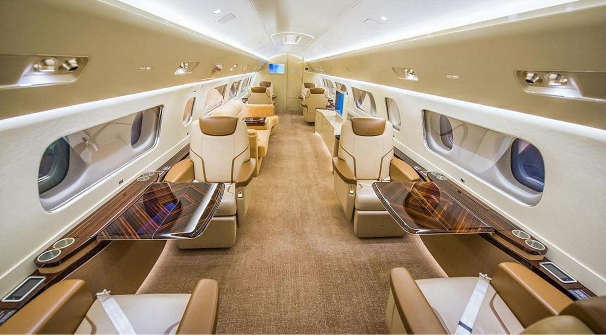 A view of the aircraft's interior, featuring tan leather seats and wood tables.