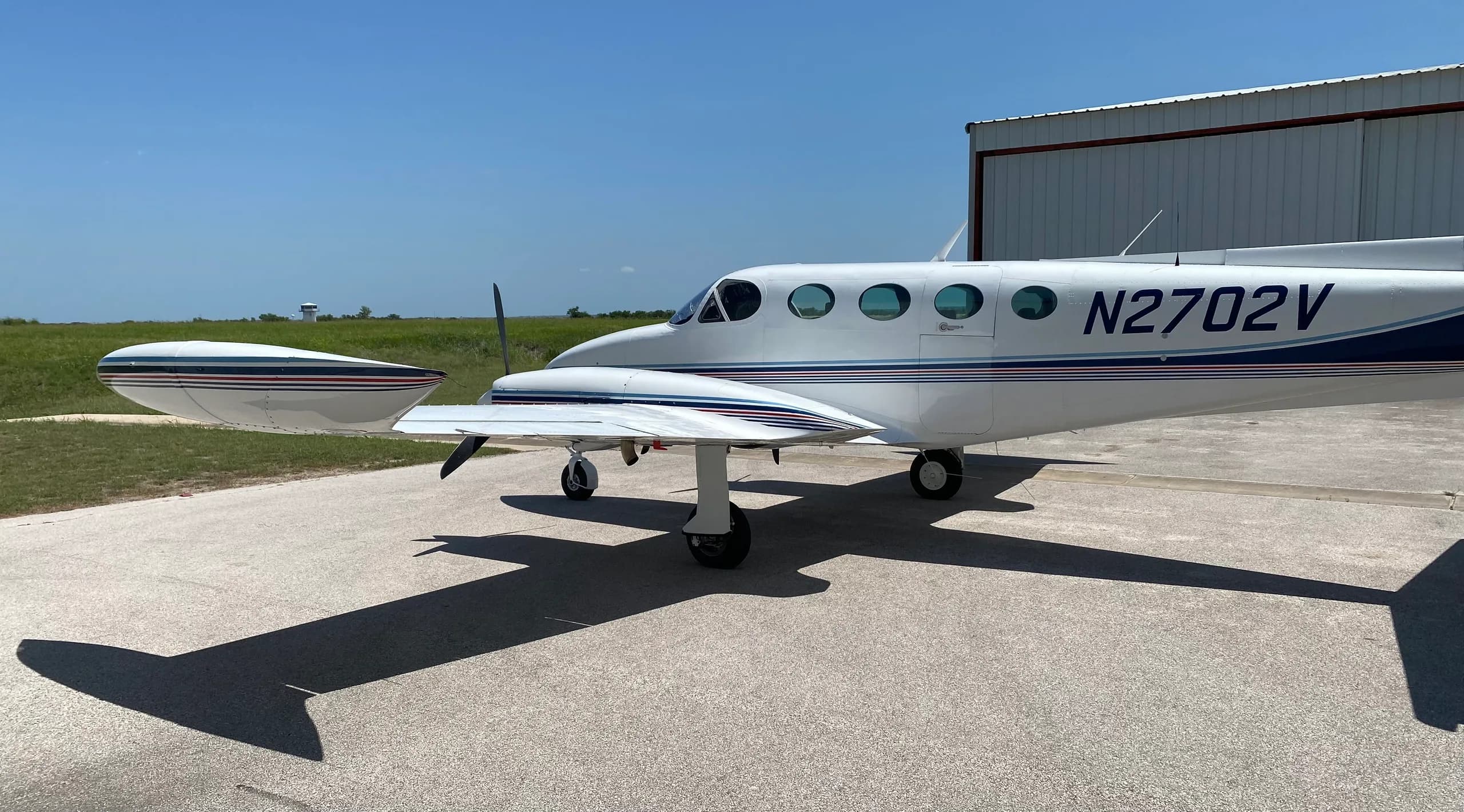A Cessna 340A aircraft with registration N2702V parked on the tarmac, side view.