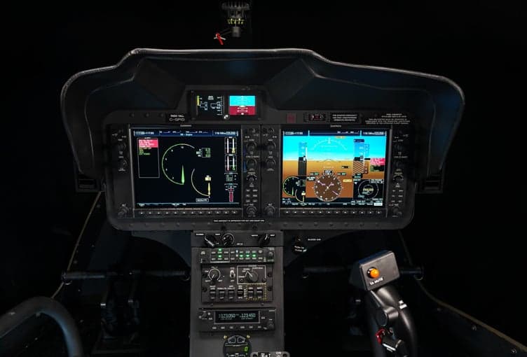 The instrument panel of a Bell 505 helicopter, featuring multiple display screens and controls.