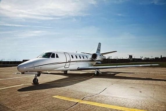 Cessna Citation CJ3 on the tarmac with a white and black paint scheme.