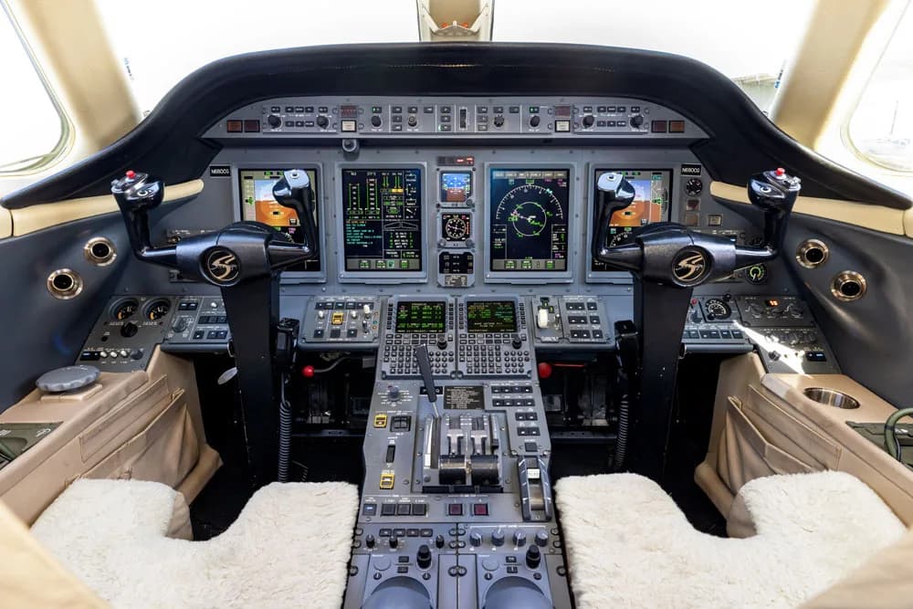 A view from the aircraft cabin looking towards the cockpit, showing wood paneling and a display.