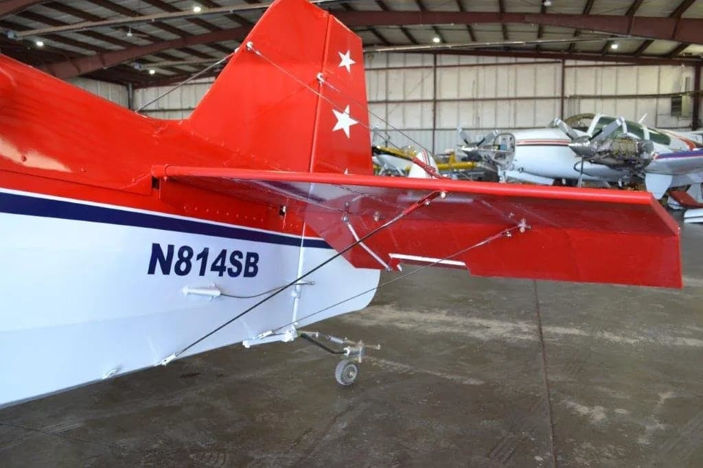 Tail section of a red and white aircraft with stars on the tail and wings, showing the tail number N814SB.