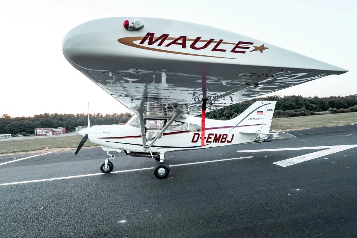 Side view of the D-EMBJ Maule STOL aircraft on the tarmac, with the door open.