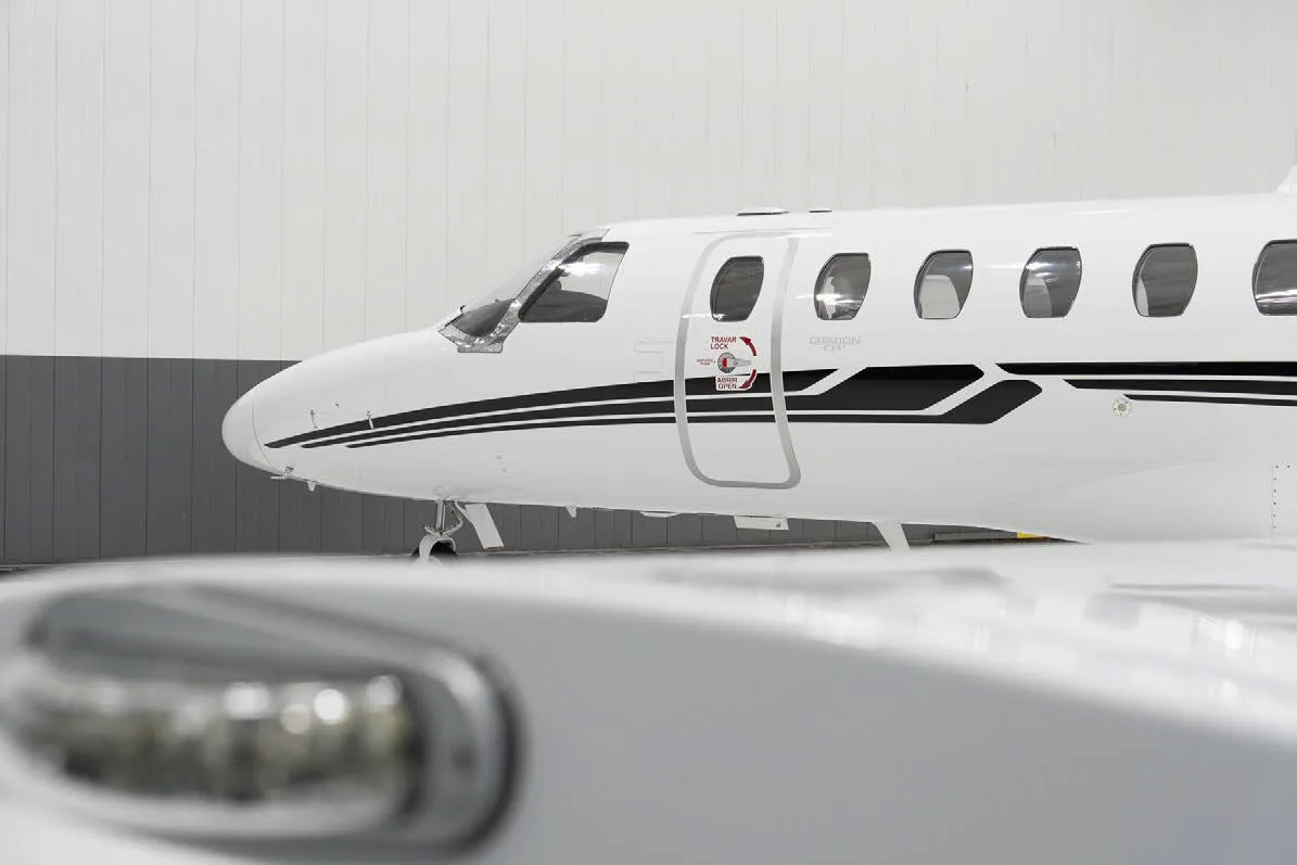 A close-up view of the front fuselage and cockpit of a white Cessna Citation CJ3 jet with black stripes.