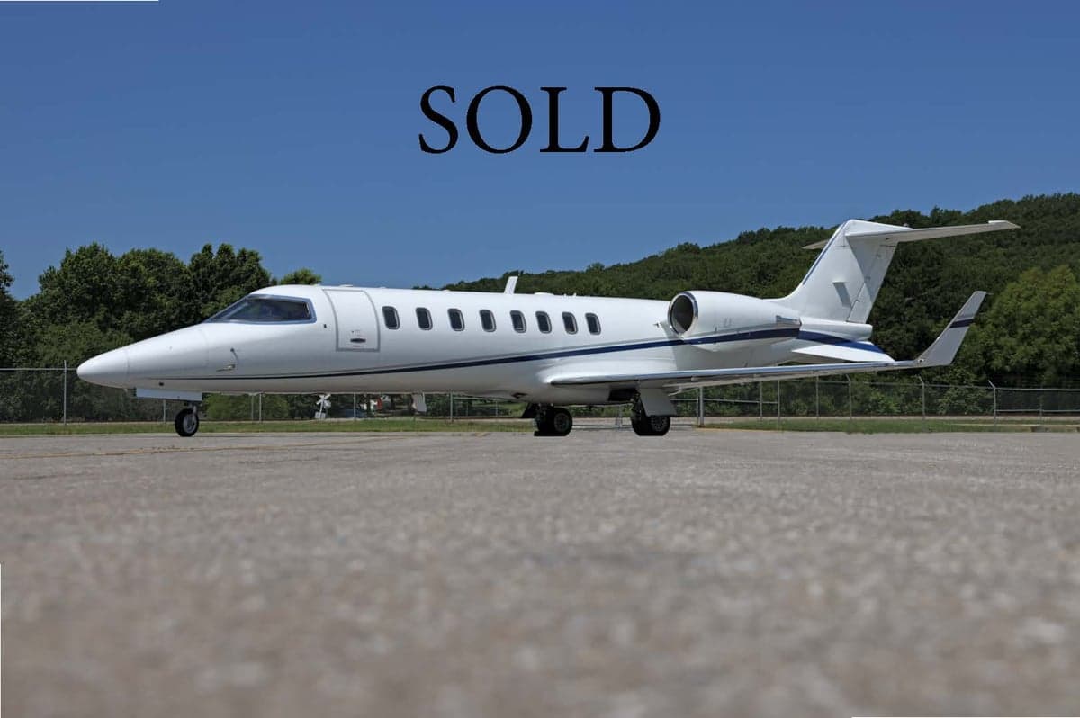 A white Learjet is parked on the tarmac with the word SOLD overlaid.