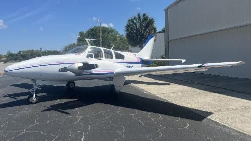 A white and blue Piper Aztec N819MC is parked on the tarmac.