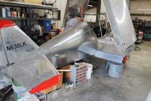 Rear view of a silver aircraft with red accents and the tail number N638LK in a hangar.