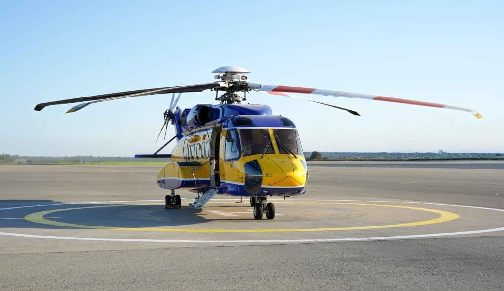 A blue and yellow helicopter with registration 4K-AZ5 on a helipad.