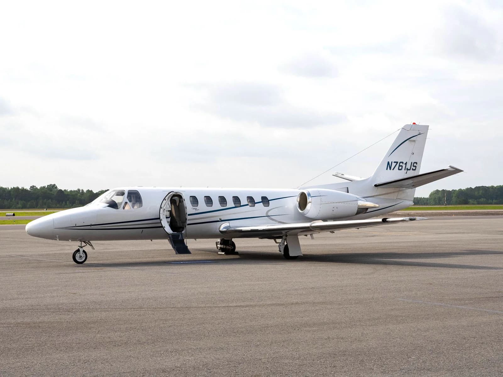 Side view of a white aircraft with registration N761JS on the tarmac.