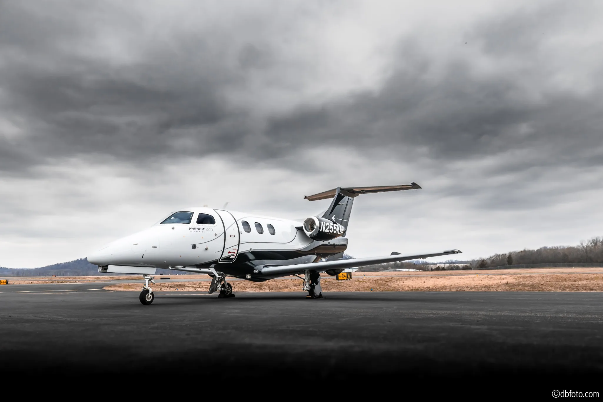 Side view of a Phenom 100EX aircraft on the tarmac.