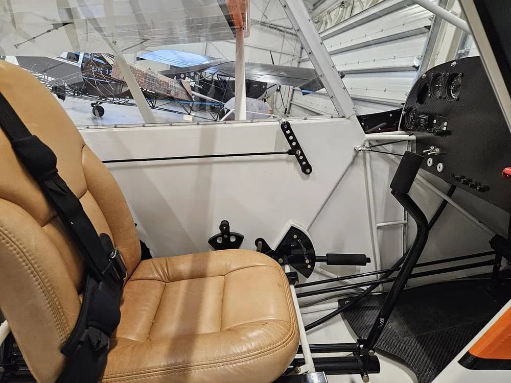 The tan pilot's seat and partial instrument panel of the aircraft, viewed from inside the cabin.