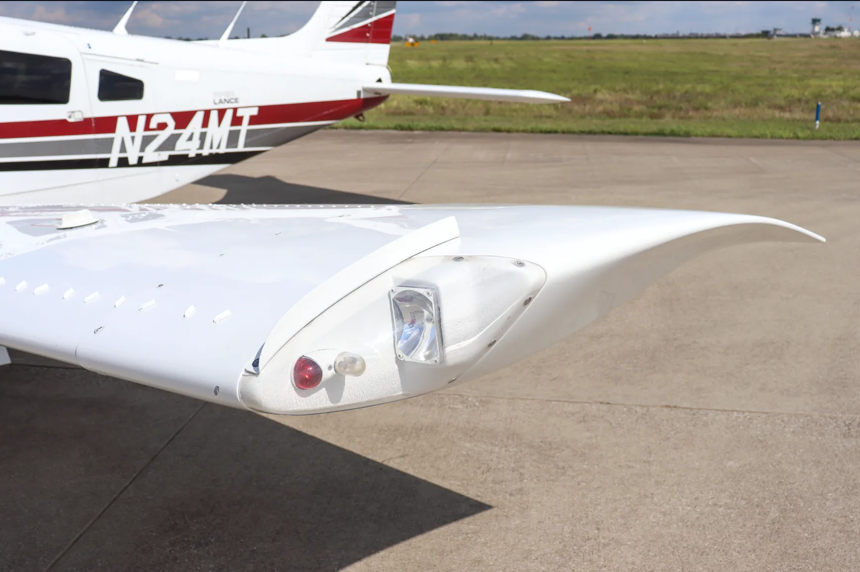 A close-up view of the white wingtip of the Piper Lance (N24MT), showing navigation lights.