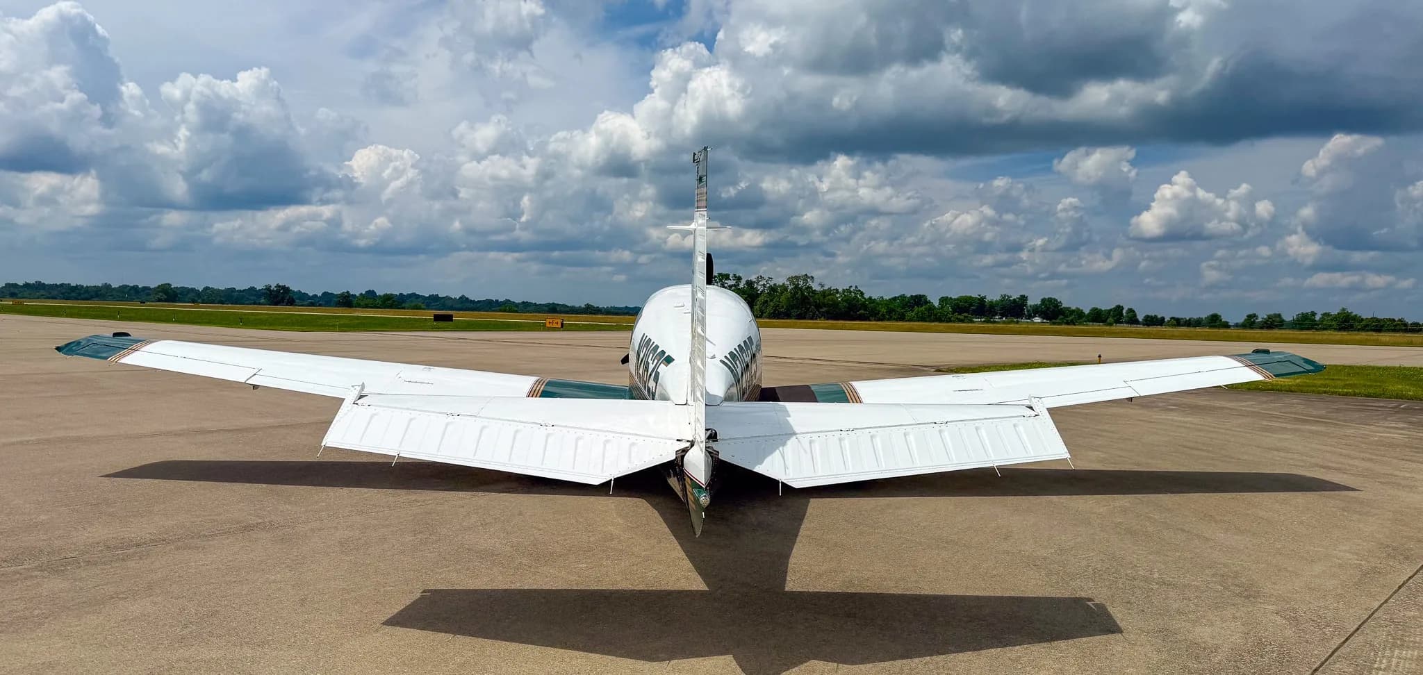 A rear view of the white and green Mooney M20 aircraft with registration N21625 on an airfield.