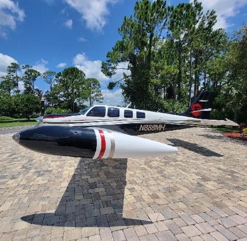 A Beechcraft Bonanza with registration N888MH is parked on a brick driveway.