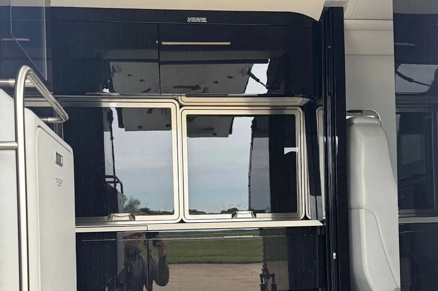 An interior view showing two aircraft windows and dark reflective cabinetry with reflections of the exterior.