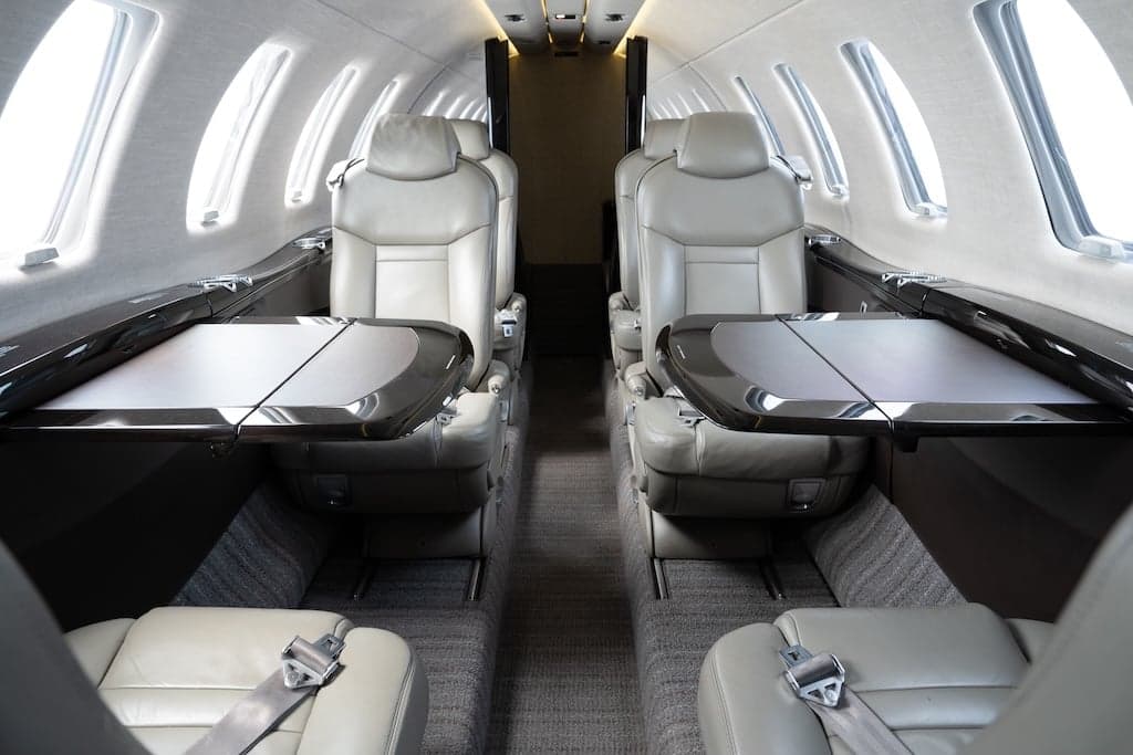 View of the aircraft's interior cabin with leather seats and fold-out tables.