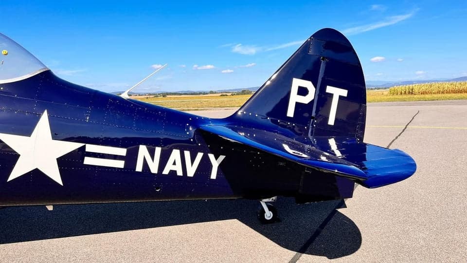 Side view of a navy blue North American T-6 Texan on the tarmac.