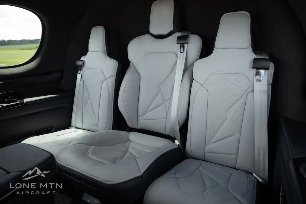 A side view of the light gray leather seats in the rear cabin of a Cirrus Vision Jet, featuring detailed stitching.